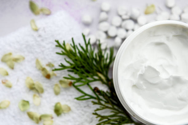 istock Close-up of a smooth moisturizer in a plastic jar on a blue background with white small stones on top. The concept of skin care. 1280272358