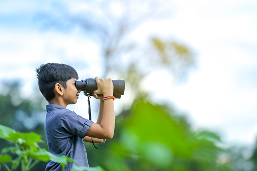 little Indian boy enjoys in nature with binoculars