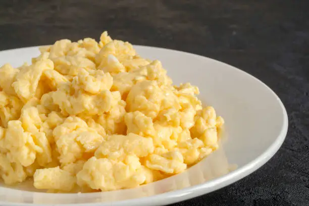 Photo of scrambled eggs on a white plate.