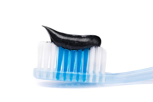 istock Closeup of blue toothbrush with black charcoal paste 1280282467