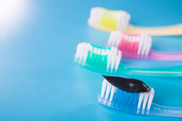 istock Set of four colorful toothbrushes with black charcoal paste 1280282724