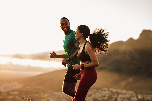 Side view of fitness man and woman running together in the morning. Fitness couple enjoying their early morning run on a hill.
