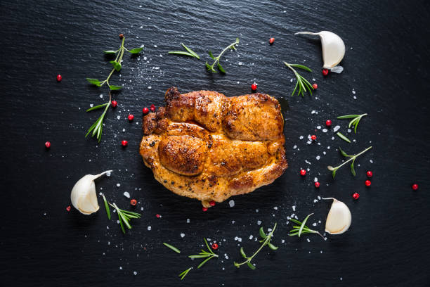 istock Grilled pork steak with spices, herbs and garlic on black background 1280284826