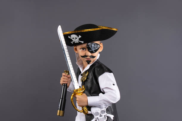 istock Classic captain pirate with face painted lunging forward with raised sword in challenging pose. Isolated on gray background with plenty of room for copy. Happy Halloween 1280284979