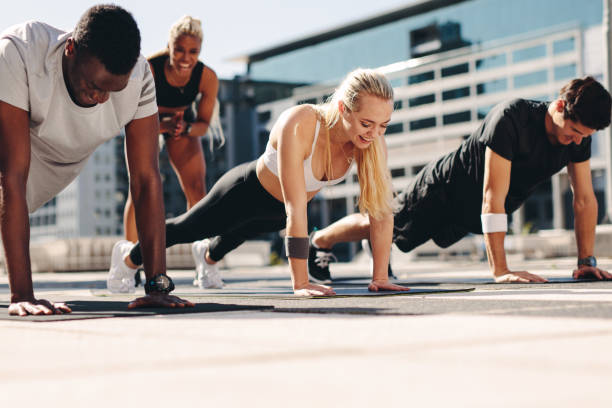 istock Group of people doing push ups outdoors 1280286123