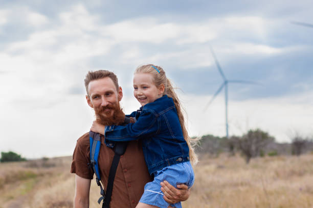 padre con la figlia in mano in piedi sulla collina con la natura lanscape. bambina bionda che sorride e abbraccia papà all'aperto. - action family photograph fathers day foto e immagini stock