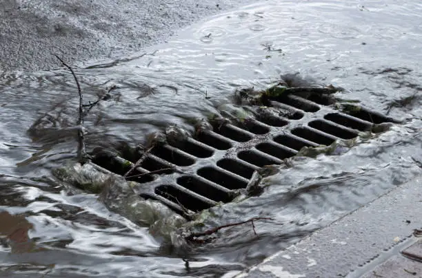 Rainwater flows into a storm sewer. City sewage system for draining water during heavy rain