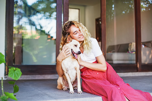 Pretty young caucasian woman hugging her pet dog at home
