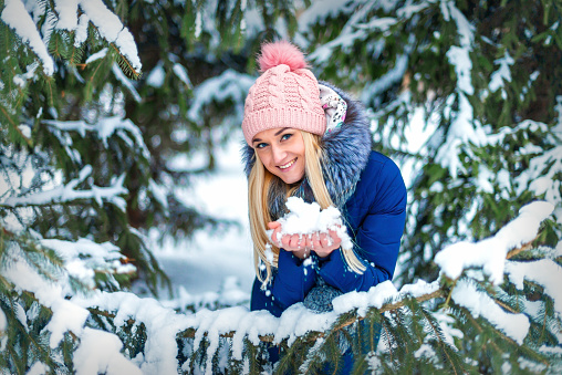 Portrait of beautiful young caucasian woman with snow in her hands