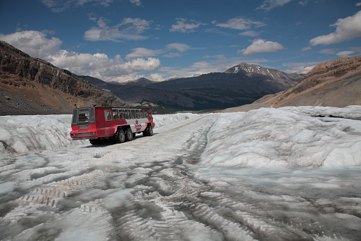 Ice Explorer massive vehicle snow coach bus driving on the ice road to  Athabasca Glacier during summer  in the boundary of Banff and Jasper National Park, Canadian Rockies, Alberta, Canada.