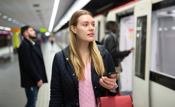 istock Female passenger with phone waiting for subway train 1280304637