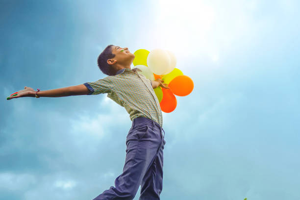 pequeño niño de la escuela india saltando en el cielo con globos tricolores y celebrando la independencia o el día de la república de la india - child patriotism saluting flag fotografías e imágenes de stock