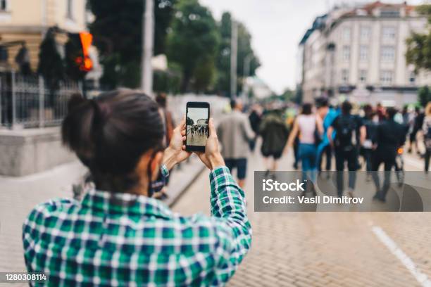 Young Man Recording A Video Taking A Photo Of A Crowd Of People Protest Procession In The City Mobile Journalism Concept Stock Photo - Download Image Now
