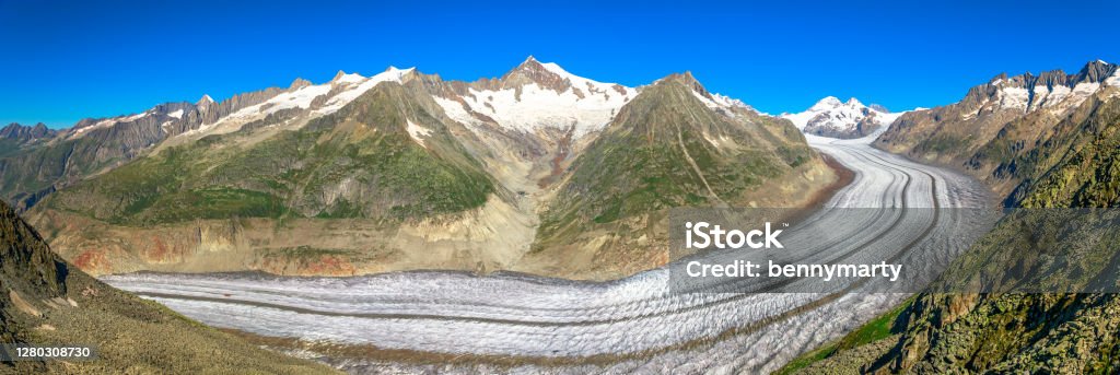 Glacier Switzerland Panorama Banner panorama of largest glacier in the Alps, the Aletsch Arena Glacier, the largest glacier from Eggishorn summit viewpoint in Canton of Valais, Switzerland, Europe. Summer season, clear blue sky. Aletsch Glacier Stock Photo