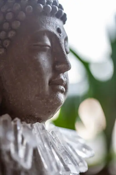 Close up detail still life of Buddha statue with crystal quartz necklace