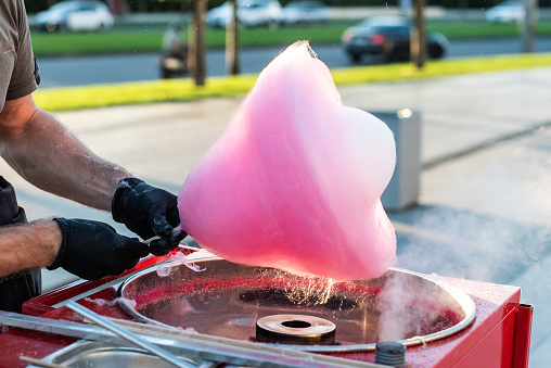 hands in black gloves make cotton candy pink. sweetness for children for a holiday. goodies.