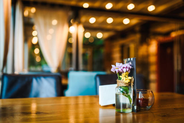 istock Wooden restaurant table with simple fresh flowers decoration on it. Cozy restaurant / cafe table. 1280312018