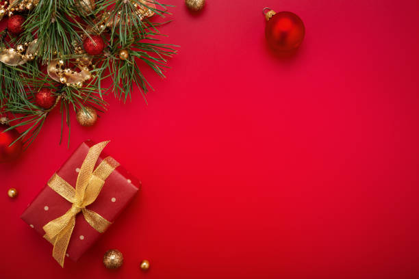 istock Christmas gift and fir tree with gold decorations on red background. 1280313765