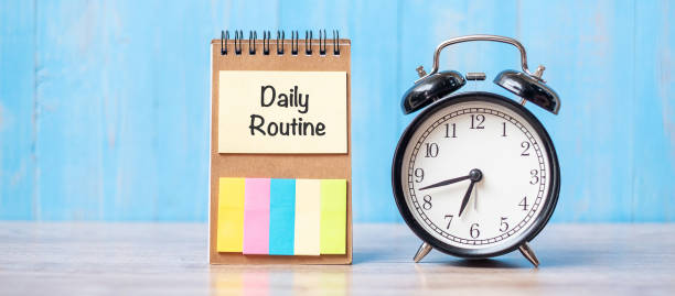 istock alarm clock with Daily Routine note paper on wooden table background and copy space for text. Activity, morning coffee break, workout and Work life balance concept 1280313887