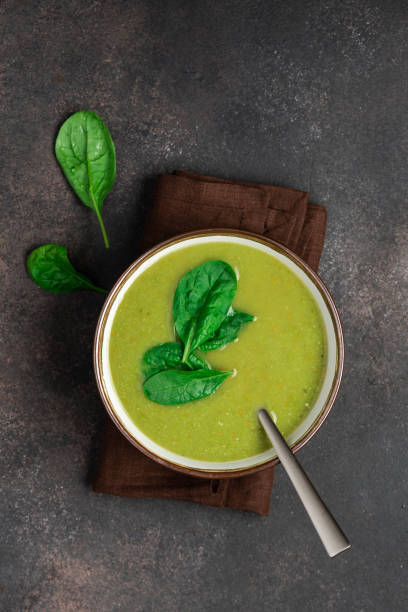 Spinach cream soup in a bowl. Brown concrete background, top view stock photo