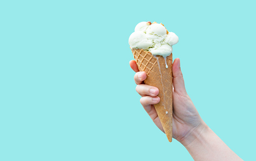 Woman hand holding vanilla ice cream, delicious desserts in summer, high-calorie food.