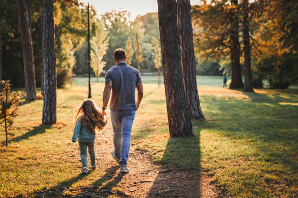 istock Father and daughter walking in public park at sunset 1280317580