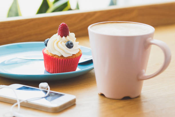 istock Small cupcake with raspberry and blueberry and a cup of hot cappuccino 1280317681