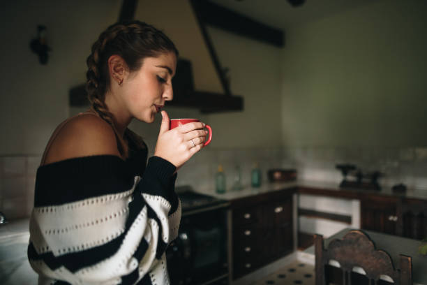 istock Young woman drinking from a cup in a kitchen 1280319369