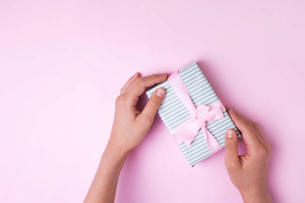istock Hands hold a gift on a pink background. View from above 1280320799