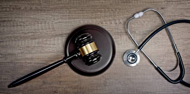 istock Judge gavel beside medical stethoscope on wooden table. Panoramic image. 1280320842