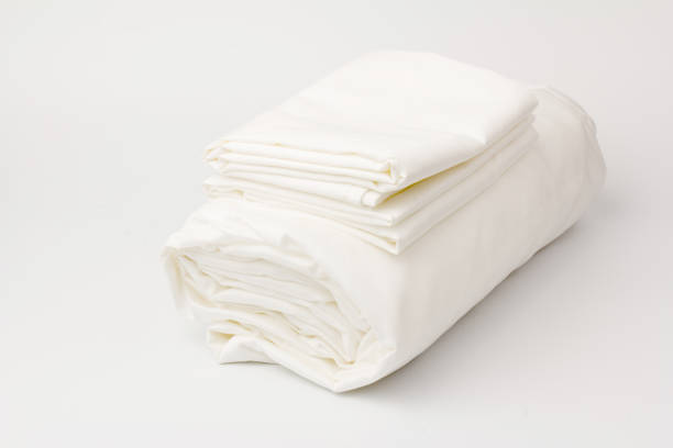 istock Stack of clean bed sheets on white  background, closeup. 1280321284