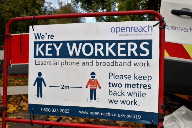 BT Openreach sign saying we're key workers, essential phone and broadband work, please keep two metres back while we work Chorleywood, Hertfordshire, England, UK - October 15th 2020: BT Openreach sign saying we're key workers, essential phone and broadband work, please keep two metres back while we work british telecom photos stock pictures, royalty-free photos & images