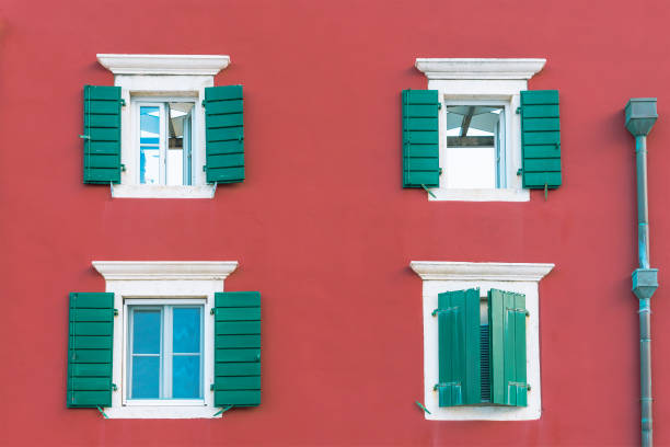 Dark red facade of old building with green shutters.