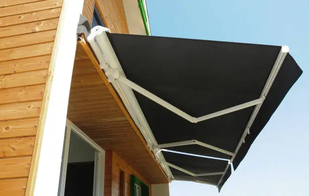 Photo of Outdoor high quality automatic sliding canopy retractable roof system, patio awning for sunshade of a modern wooden house.