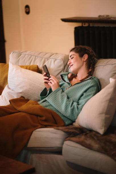 istock Young woman sitting on sofa and using phone 1280325640