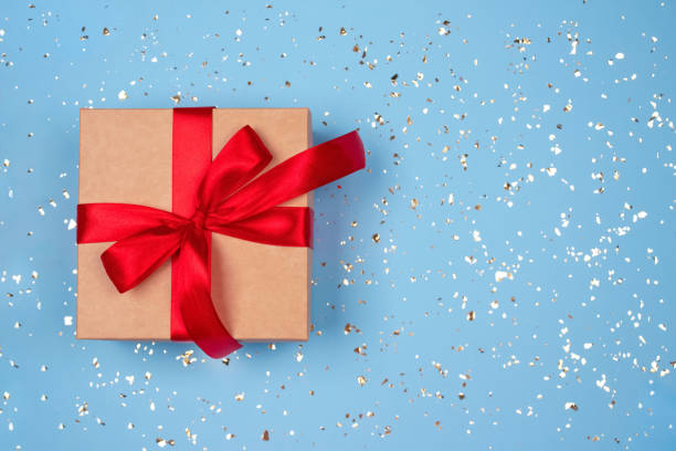 istock Gift box with red bow on festive blue background with golden sparkles around and copyspace for your text. Flat lay style. Christmas, New Year, Valentines Day or birthday celebration concept 1280325810