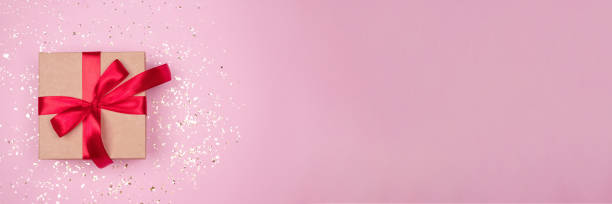 istock Gift box with red bow on festive pink background with golden sparkles around and copyspace for your text. Flat lay style. Christmas, New Year, Valentines Day or birthday celebration concept. Banner 1280325812