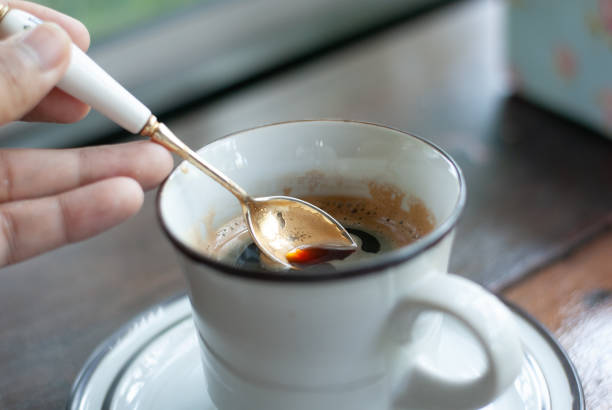 istock A hand holding silver spoon scooping some hot black coffee from a white ceramic mug, morning feel 1280327096