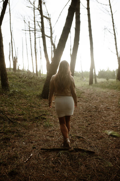 istock Rear view of a young woman walking in a forest 1280328005