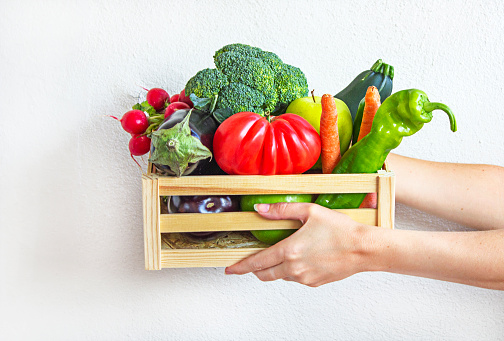 Manos sosteniendo caja de verduras frescas photo