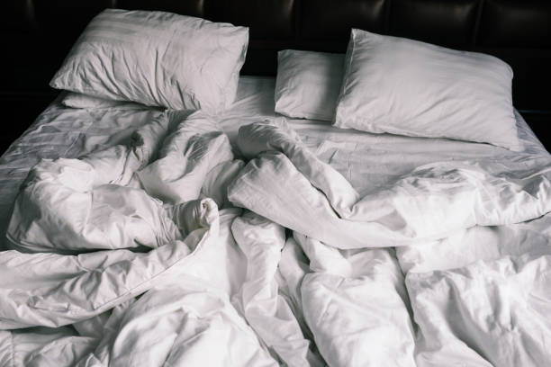 Unmade Bed with White Wrinkled Sheets and a Blue Blanket Captured in Natural Morning Light. The Scene Reflects Everyday Life, Rest, Relaxation, and Authentic Home Atmosphere.