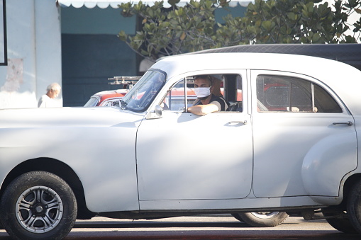 Havana - CUB; march 23, 2020: A driver drives a classic car in havana with a face mask to protect himself from the coronavirus
