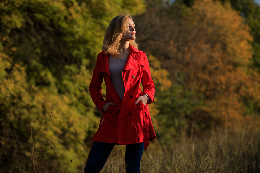 Portrait of elegant woman in red coat at autumn trees