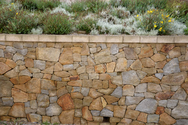 istock beautifully folded retaining wall with a granite attic with small joints. brown beige yellow irregular gneiss stone holding a slope above it. there are undemanding perennials around 1280336397
