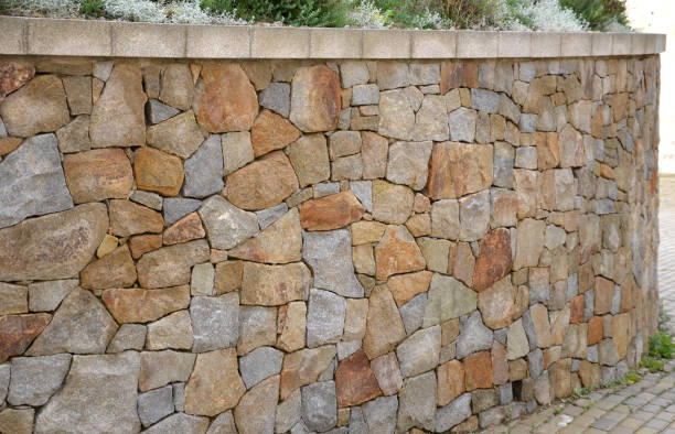 istock beautifully folded retaining wall with a granite attic with small joints. brown beige yellow irregular gneiss stone holding a slope above it. there are undemanding perennials around 1280336406