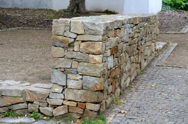 istock beautifully folded retaining wall with a granite attic with small joints. brown beige yellow irregular gneiss stone holding a slope above it. there are undemanding perennials around 1280336555