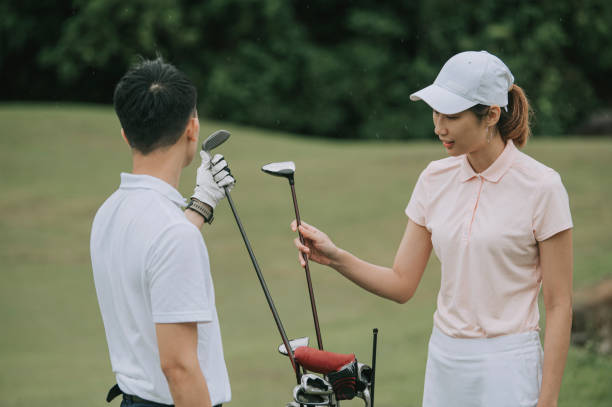 asiatische chinesische junge paar golfer nehmen golfschläger aus golftasche auf dem golfplatz - golf golf course putting green hole stock-fotos und bilder