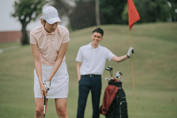 아시아 중국 여자 골퍼 퍼팅 공 와 남성 파트너 들고 플래그 에 골프 코스 - golf putting determination focus 뉴스 사진 이미지