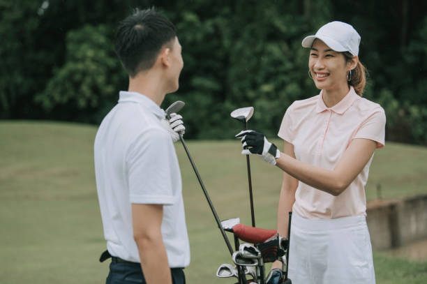 asiatische chinesische junge paar golfer nehmen golfschläger aus golftasche auf dem golfplatz - golf golf course putting green hole stock-fotos und bilder