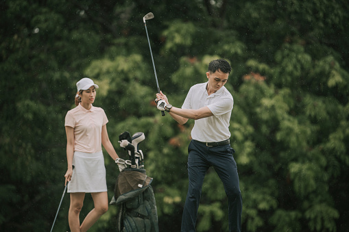 Asian chinese male golfer teeing off and swing his driver club on the golf course